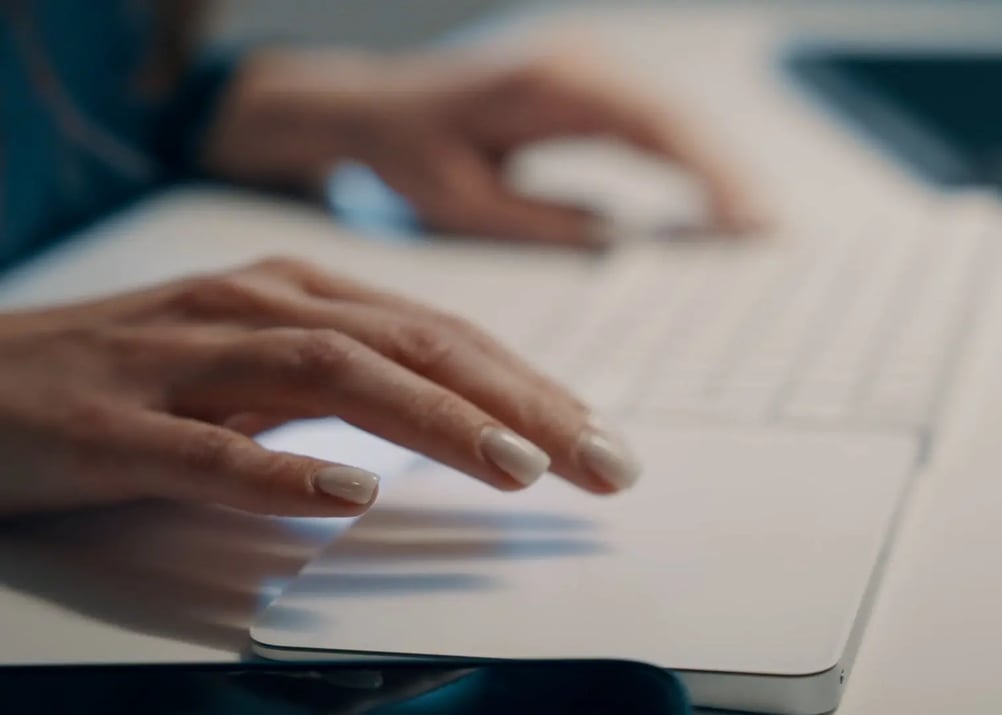 En persons händer som skriver på ett vitt tangentbord